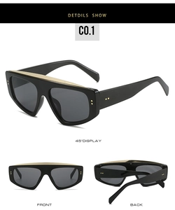 Macro detail of oversized black sunglasses with top gold trim and deep gray lenses