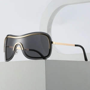 Futuristic Y2K oversized wrap-around sunglasses with gold metal trim and grey lenses