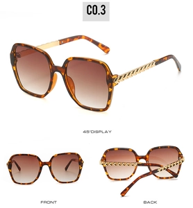 Detail view of large tortoise shell sunglasses with gold chain temples and brown gradient lenses