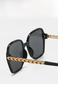 Detail of fashion sunglasses featuring gold fish-scale textured metal temple design
