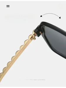Macro view of durable gold metal wave hinge on black oversized square sunglasses
