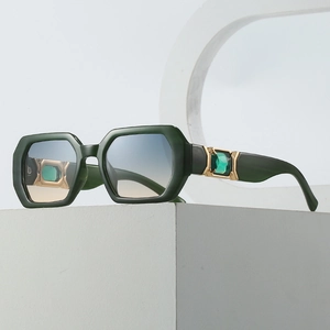 Polygonal sunglasses with dark green geometric frame and emerald gemstone detail on temple
