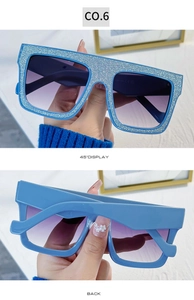 Detail van vierkante oversized zonnebril met blauwe glitter montuur en verloopglazen