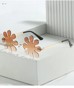 Detail of flower-shaped rimless sunglasses lens with gold metal arms and gradient brown tint