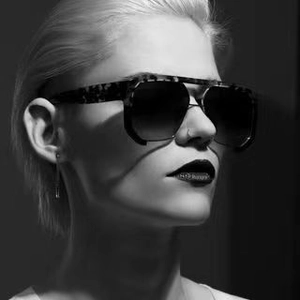 Artistic black and white close-up of oversized tortoise shell sunglasses on a model