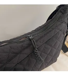 Dettaglio della zip in metallo e del tirante intrecciato sulla borsa in nylon trapuntata