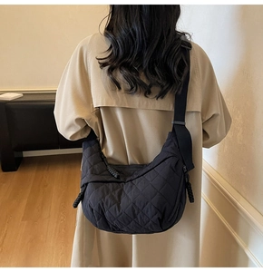 Vista posteriore di una modella con una grande borsa a tracolla in nylon nero trapuntato