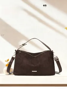 Detail of dark brown suede tote bag featuring a gold zipper and minimalist metal trim