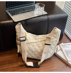 Dettaglio della borsa a mezzaluna in nylon trapuntato crema con motivo a rombi e tirazip a treccia