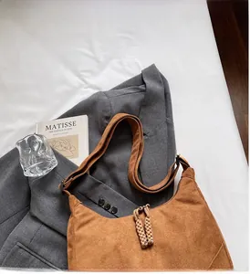 Dettaglio di una borsa hobo in camoscio marrone con tirazip intrecciato e morbido