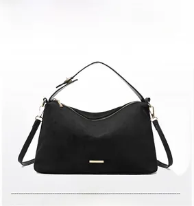 Detail of black suede tote bag featuring golden hardware and versatile shoulder straps