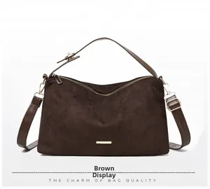 Detail of dark brown suede shoulder bag with gold hardware and adjustable strap
