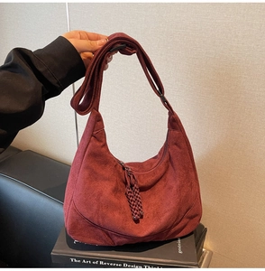 Dettaglio della borsa hobo in pelle scamosciata bordeaux con nappa intrecciata e forma morbida