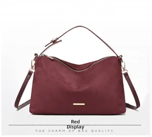 Close-up of wine red suede tote bag with gold metal hardware and smooth zipper detail