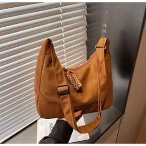 Dettaglio borsa a mezzaluna in camoscio marrone con tracolla larga e ciondoli intrecciati