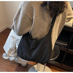 Dettaglio della borsa hobo nera con nappa in corda intrecciata e tracolla regolabile