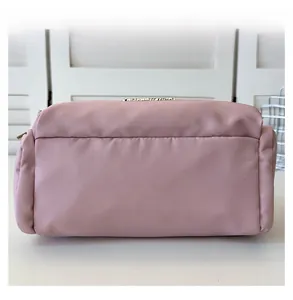 Close-up of fine stitching and metal brand logo on pink nylon tote bag detail