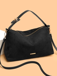 Elegant black suede tote bag with gold hardware and logo on warm background