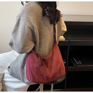 Dettaglio della borsa hobo in pelle scamosciata bordeaux con nappa intrecciata indossata