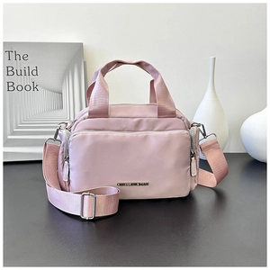 Macro detail of a pale pink nylon tote bag with silver hardware and a branded metal logo