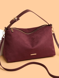 Detail of burgundy faux suede tote bag with gold zipper and smooth leather accents