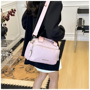 Detail view of pink multi-pocket nylon tote bag showing strap textures and metal logo
