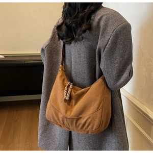 Dettaglio di una borsa hobo marrone con tirazip intrecciati su un cappotto di tweed