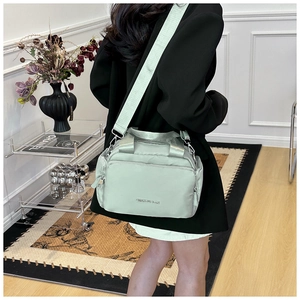 Close-up of mint green nylon tote bag featuring multiple pockets and a wide shoulder strap