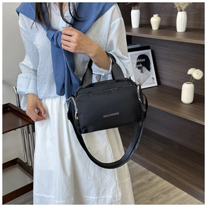 Detail of black nylon tote bag showing multiple zippers and adjustable shoulder strap