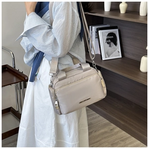 Detail of multi-pocket nylon tote bag in apricot with adjustable straps and metal logo