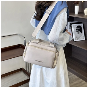 Detail showing the adjustable wide shoulder strap and brand text on beige tote bag