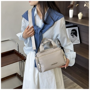 Detail view of stylish beige nylon tote bag with wide strap on a fashion model
