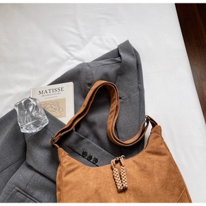 Dettaglio borsa hobo in pelle scamosciata marrone con tiranti intrecciati e stile urban