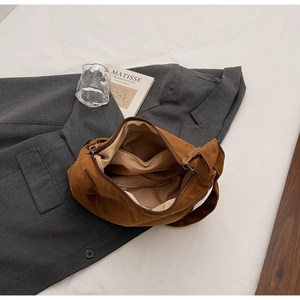Dettaglio borsa hobo in pelle scamosciata caramello con zip su blazer grigio
