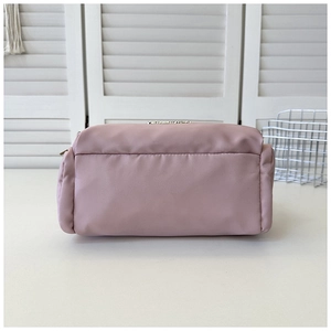 Detail view of pink nylon tote bag with top zipper closure and metal brand emblem