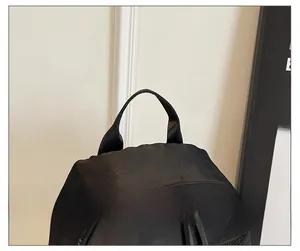 Close-up of comfortable handle and smooth metal double zippers on black nylon backpack