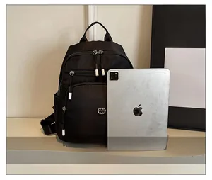Size comparison of black nylon backpack next to an iPad showing large storage capacity
