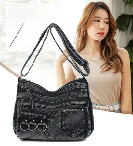 Close-up of a washed denim crossbody bag with multi-pocket design and rivet details