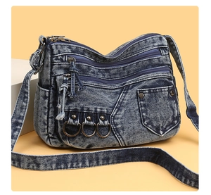 Detail of vintage blue denim crossbody bag with multiple zippers and metal hardware