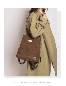 Zaino vintage marrone con motivo floreale indossato da una modella in cappotto verde