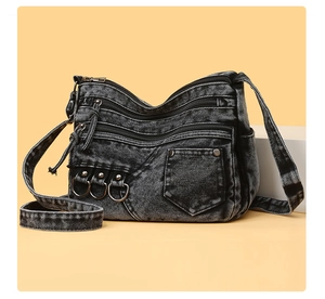 Detail of dark washed denim crossbody bag featuring multi-zipper pockets and metal D-rings