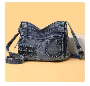 Macro view of vintage washed denim crossbody bag featuring multiple pockets and metal studs