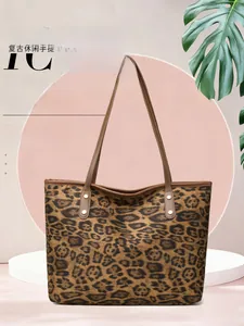 Detail of leopard print tote bag featuring brown faux leather handles and metal rivets