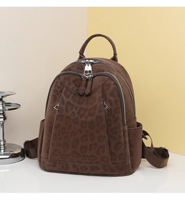 Close-up of leopard print backpack with silver zippers and multi-compartment details