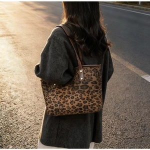 Detailed view of leopard print tote bag with brown leather strap and rivet details