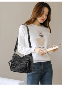 Detail view of multi-pocket washed denim crossbody bag showing zippers and metal rings