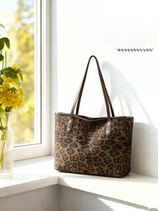 Close-up of leopard print tote bag with brown leather strap and metal rivet details