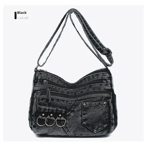 Detail view of washed denim crossbody bag featuring multiple pockets and metal ring accents