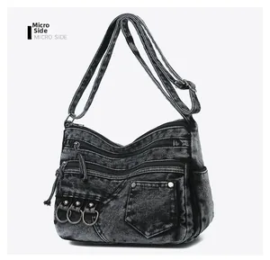 Detailed side view of washed denim crossbody bag featuring multiple zippers and metal rings