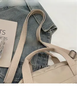 Detail of adjustable woven shoulder strap and metal hardware on beige tote bag